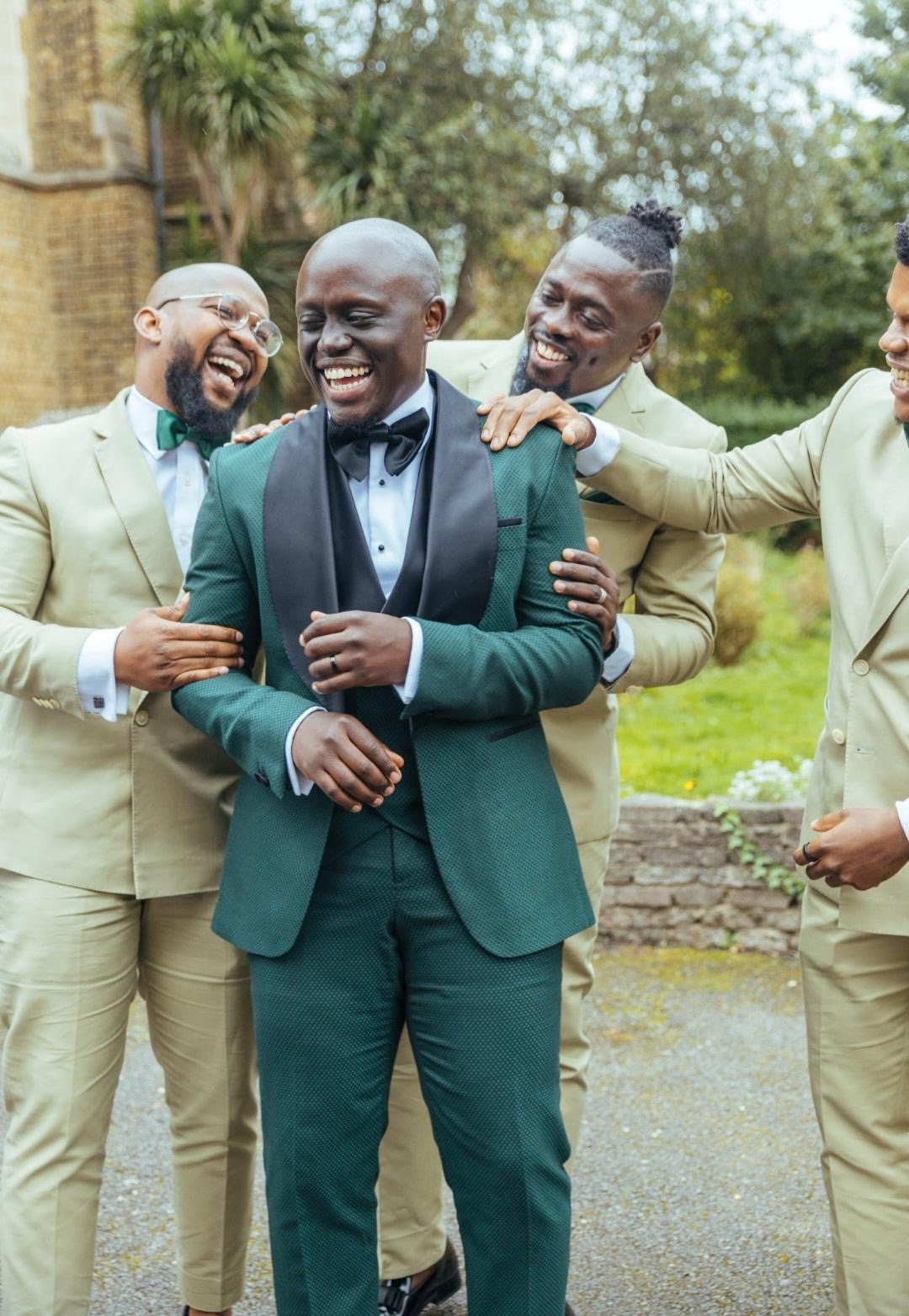 Groom laughing with his groomsmen in sage suits
