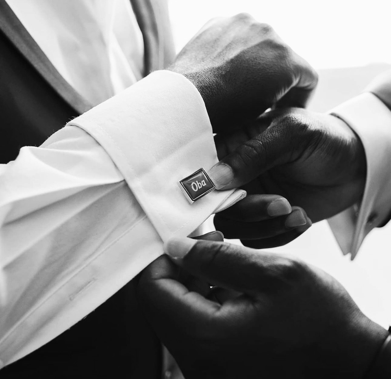 Black and white close-up of personalised cufflinks being fastened